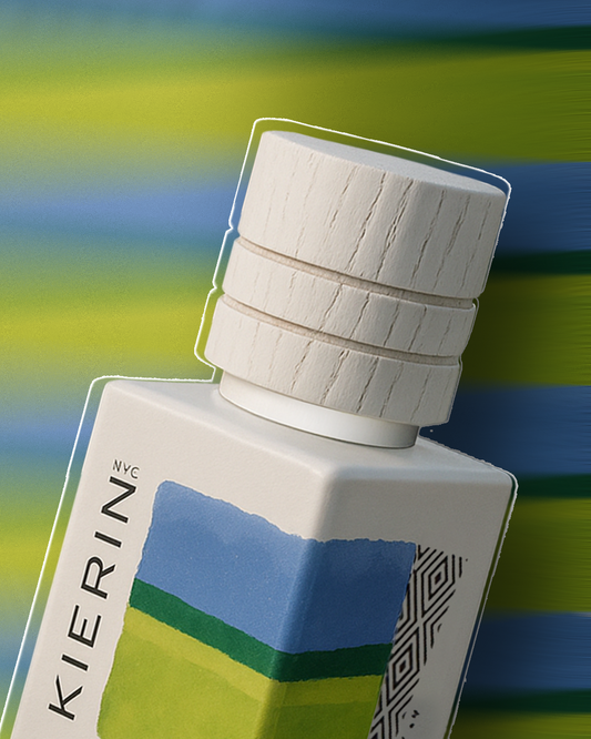 Perfume bottle with a textured white cap, featuring abstract blue and green patterns on the label against a blurred blue and green background. Modern and vibrant.