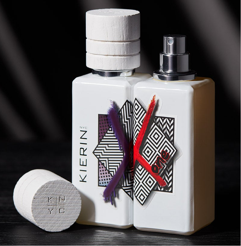 White perfume bottles with geometric labels and splashes of purple and red paint. Bold and modern design.