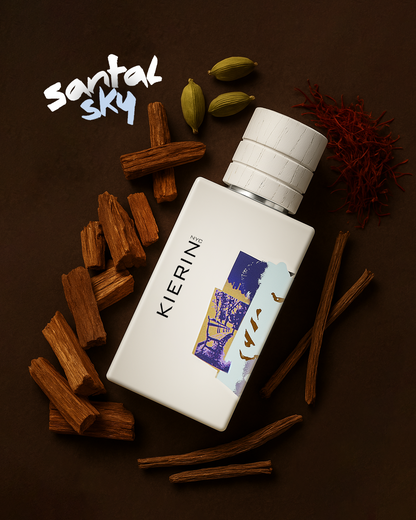 KIERIN Santal Sky perfume bottle arranged with wood and cardamom on a brown background.